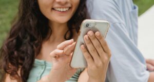 Young woman looking at a phone in her hand and smiling while leaning against a man